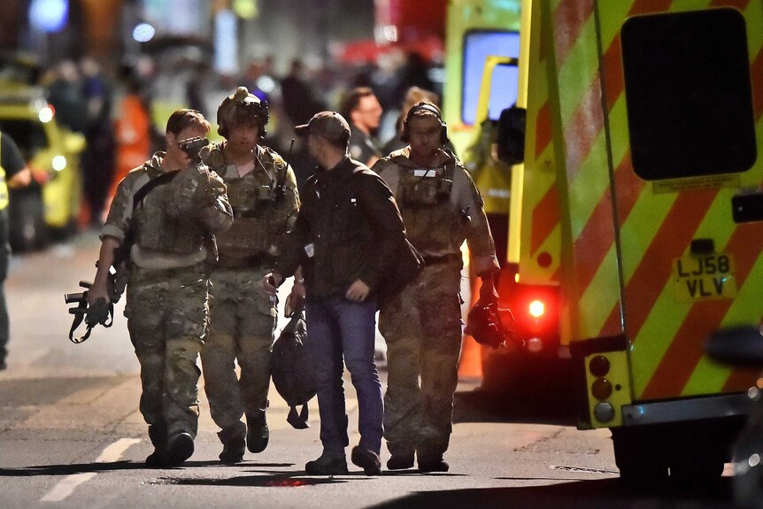 Armed officers dressed in camouflage walk down a street in London after a terrorist attack on London Bridge.