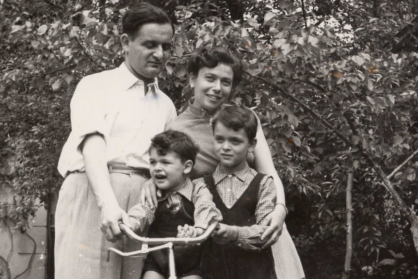 A black and white photo of a man, woman and two little boys wearing checked shirts and overalls.