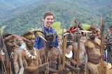 Eric Tlozek stands among villagers in tribal dress in front of mountains