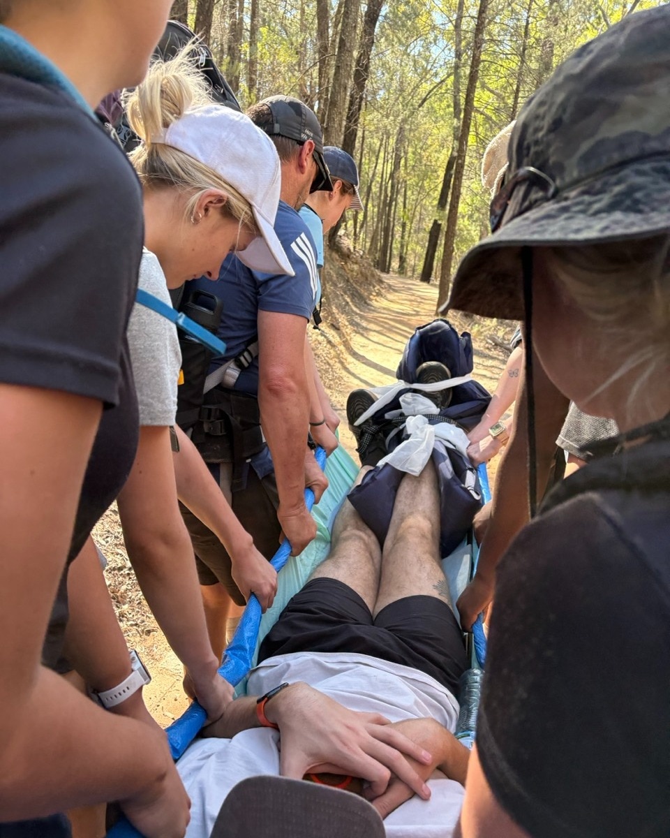 A group of girls carrying man on stretcher 