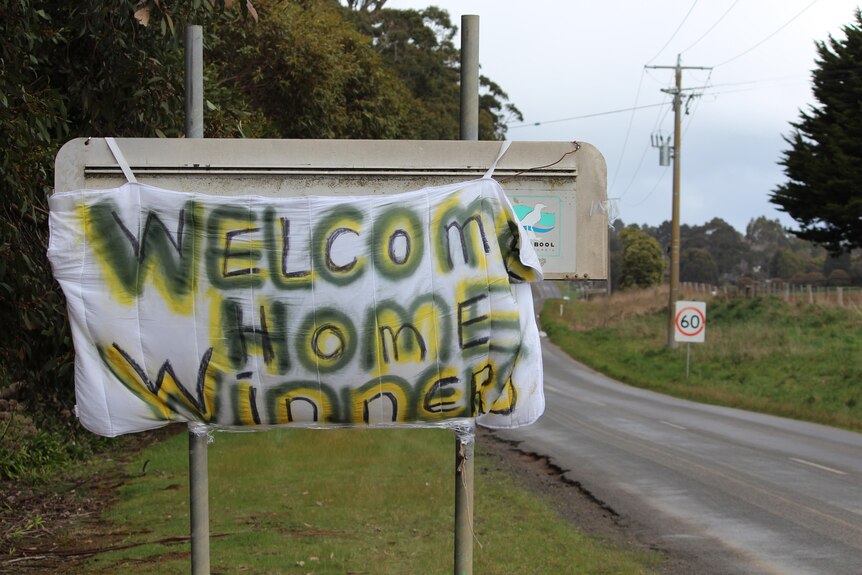 A sign in yellow and gold reads "Welcome home winners".