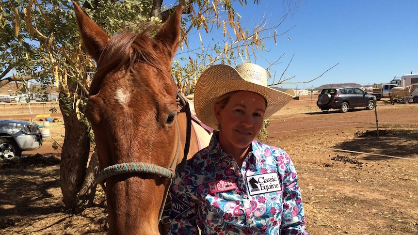 Barrel racer Jo Caldwell standing next to her horse County Roc in a camping area at the rodeo grounds in Mount Isa, Queensland.