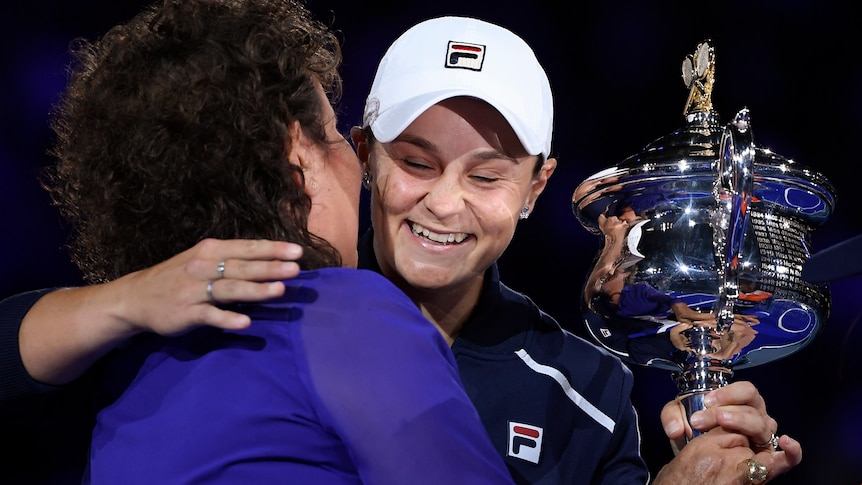 Evonne Goolagong hugs Ash Barty after the Australian Open final as she hands over the trophy.