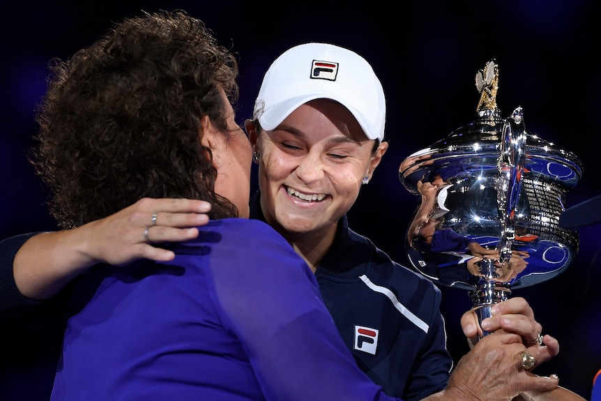 Evonne Goolagong hugs Ash Barty after the Australian Open final as she hands over the trophy.