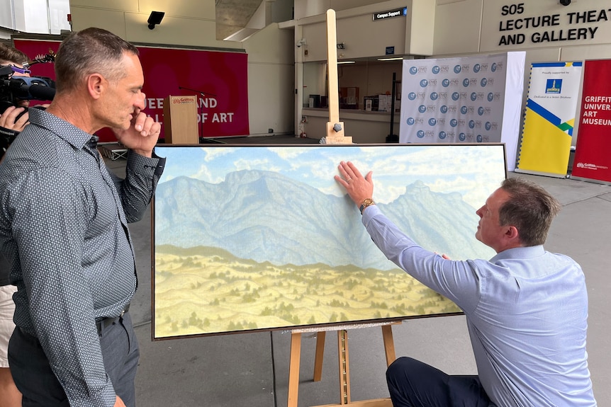 Mr Nicholson and Mr Brownhall unveiling the painting of the mountains.