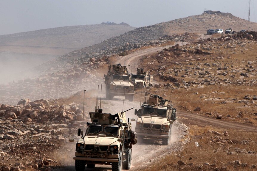A convoy of armoured vehicles drive outside Naweran near Mosul in Iraq.