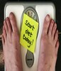 脚上贴着一张写着‘今天开始节食’的便条的体重秤。” class=