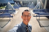 Maths teacher Eddie Woo smiles at the camera while taking a selfie outside while working.