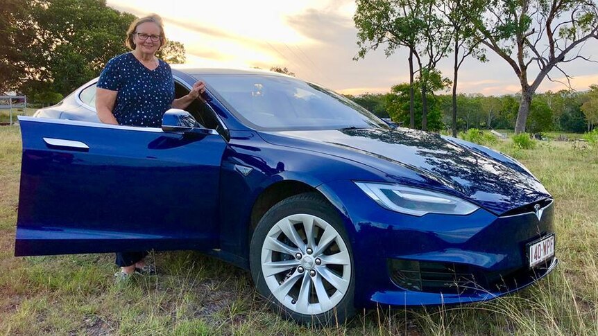 Sylvia Wilson and her electric Tesla S75 on a green field