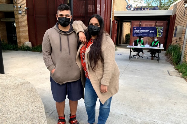 A teenage boy and his mother both wearing masks.