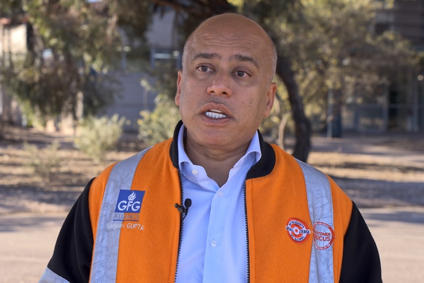 A man in a blue shirt and orange high-vis jacket that says GFG Alliance