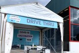 A pop-up marquee with a sign saying 'Drive thru COVID-19 vaccination hub" in front of a Bunnings building.