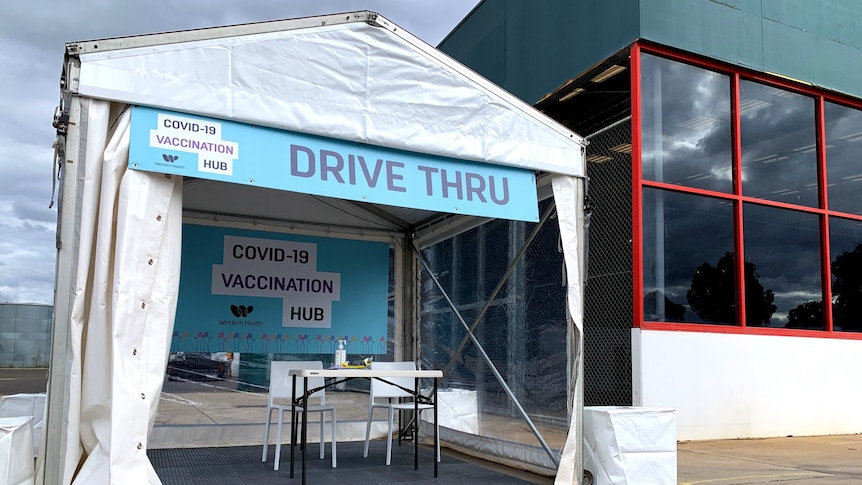 A pop-up marquee with a sign saying 'Drive thru COVID-19 vaccination hub" in front of a Bunnings building.