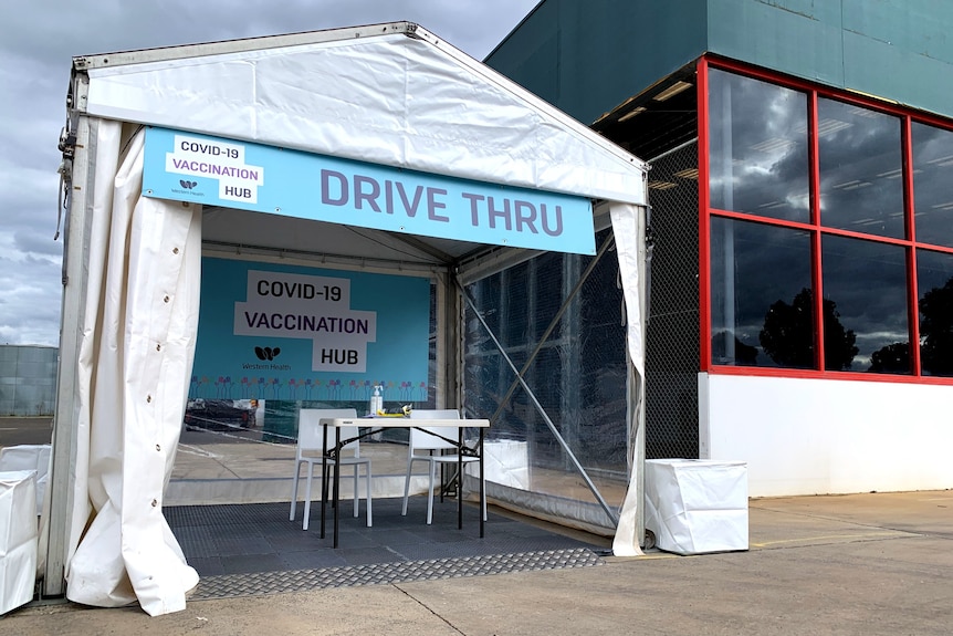 A pop-up marquee with a sign saying 'Drive thru COVID-19 vaccination hub" in front of a Bunnings building.