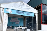 A pop-up marquee with a sign saying 'Drive thru COVID-19 vaccination hub" in front of a Bunnings building.