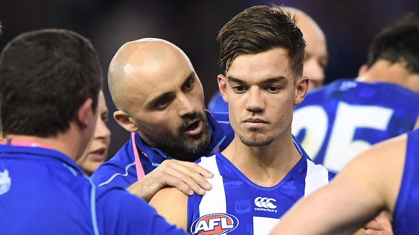 An AFL player puts bis hand on the right shoulder of one his players as he talks to him.
