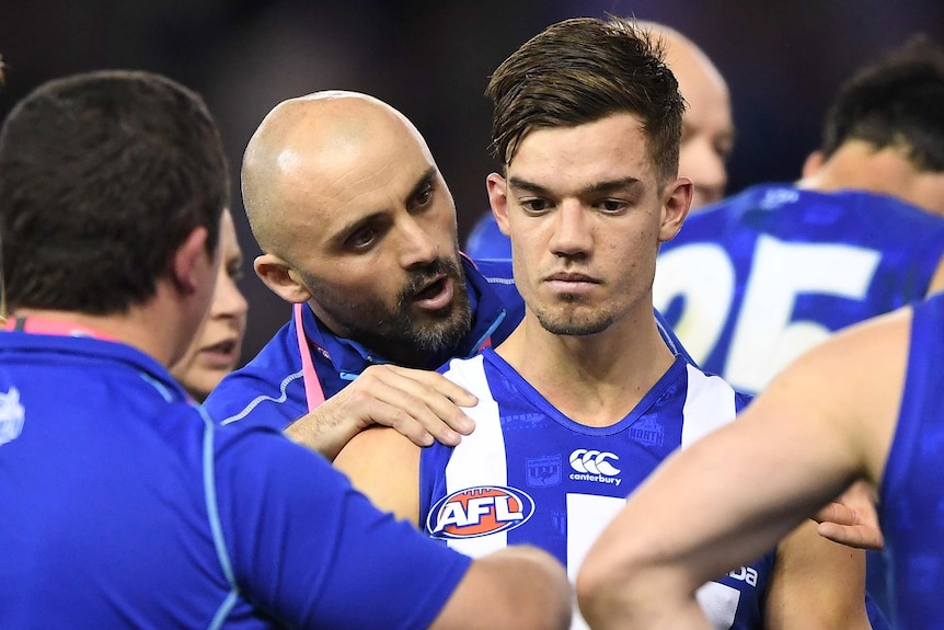 An AFL player puts bis hand on the right shoulder of one his players as he talks to him.