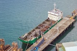 Aerial view of the wharf and ship docked with pens of cattle on deck