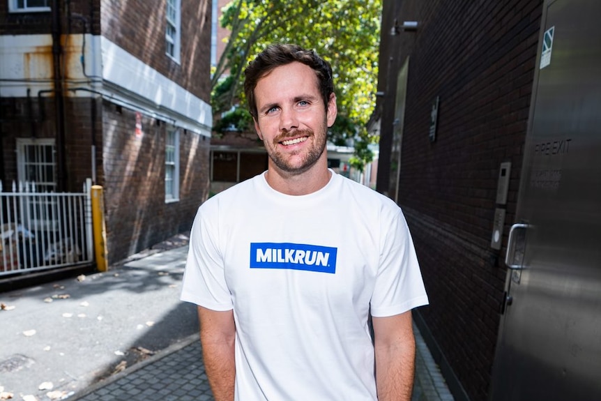 a man in a white shirt with the words milkrun on it in blue
