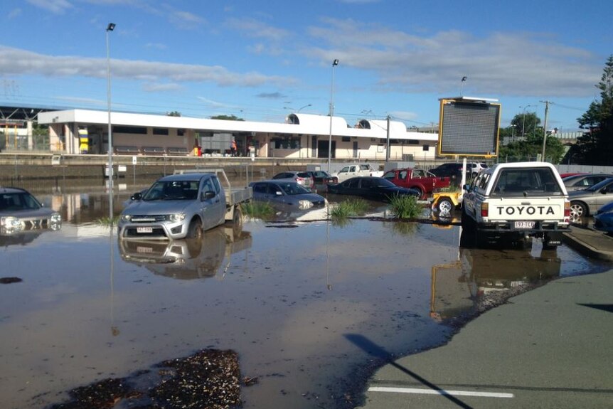 Cars parked at the train station are beginning to go under as flood waters rise.
