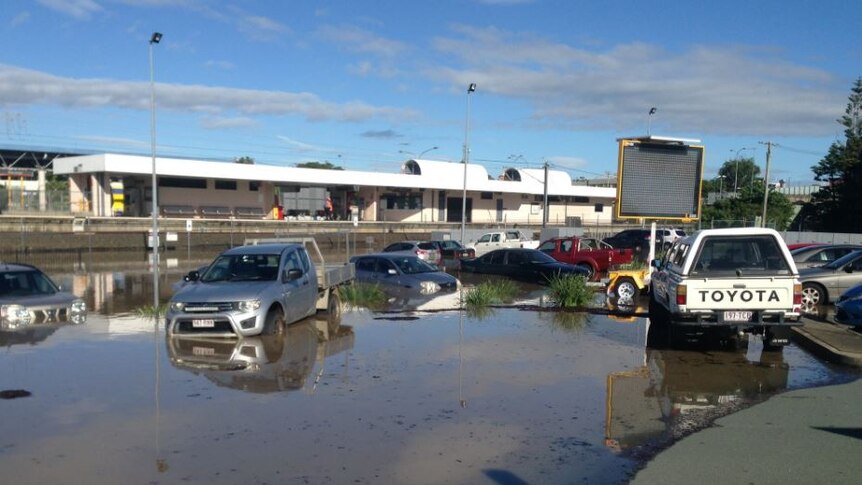 Cars parked at the train station are beginning to go under as flood waters rise.