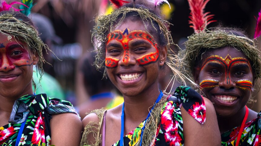 Melanesian women in traditional face paint smiling widely