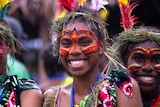 Melanesian women in traditional face paint smiling widely
