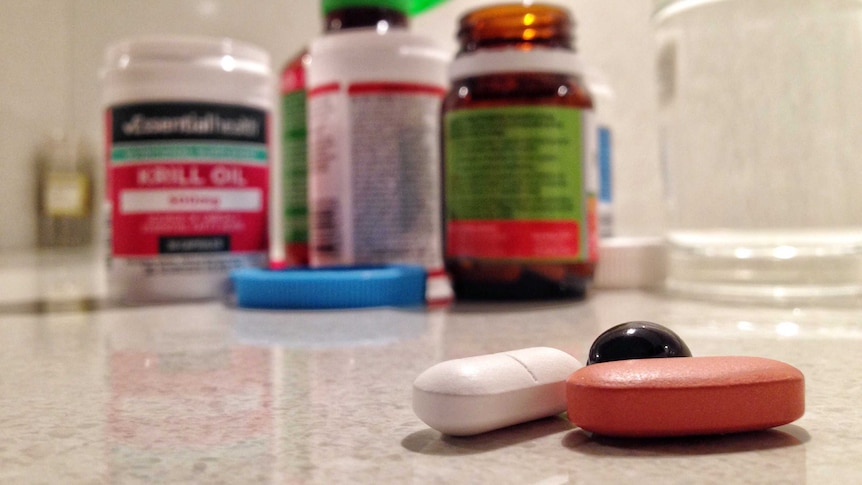 Vitamin supplements on a kitchen bench, with a glass of water.