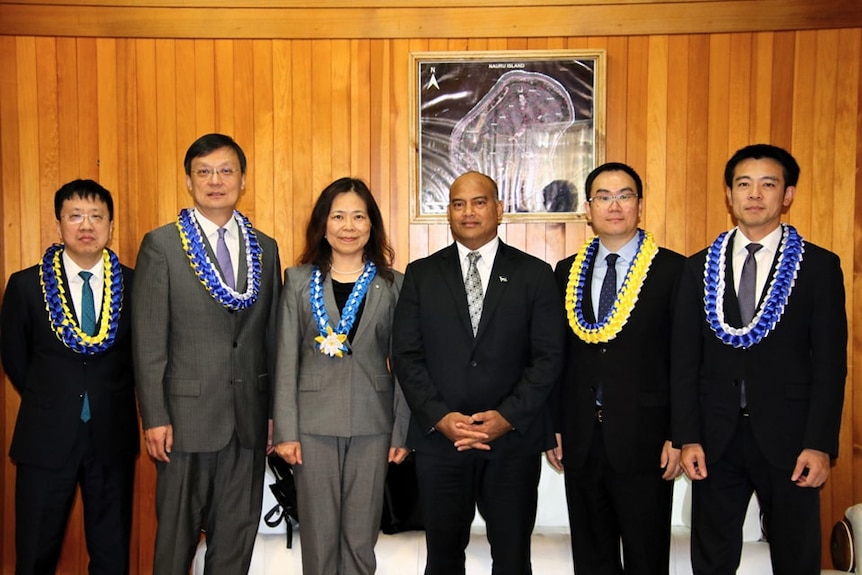 A group of five Bank of China representatives stand in line with Nauru president David Adeang. 