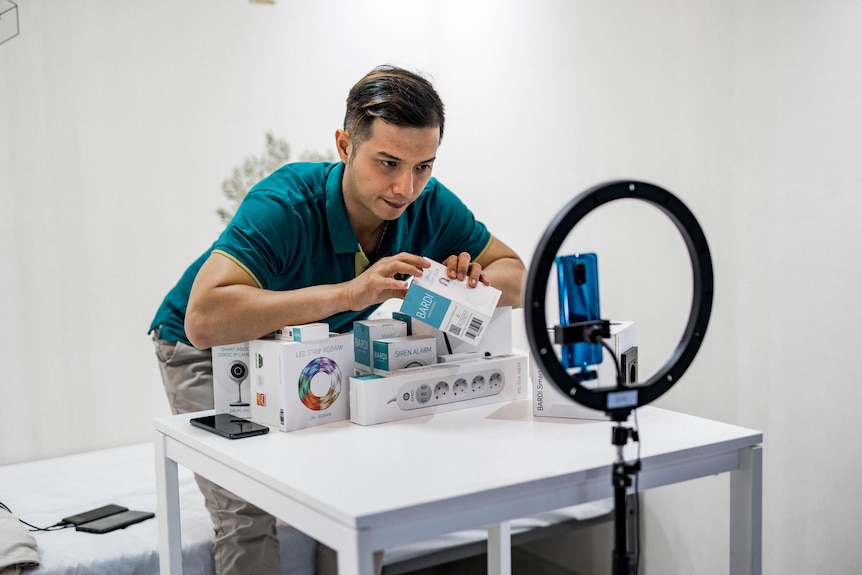 A person standing behind a table with a stack of products on it.