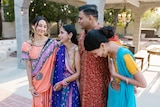 Four people standing in a row, laughing and smiling to each other