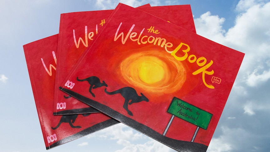 Three of the printed welcome books stacked on top of each other placed on a background of clouds.