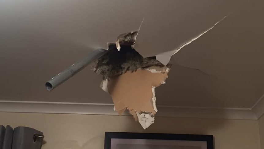 The leg of a trampoline breaks through the interior roof of a house.