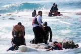 Local residents and rescue workers help a woman after a boat carrying migrants sank off the island of Rhodes.
