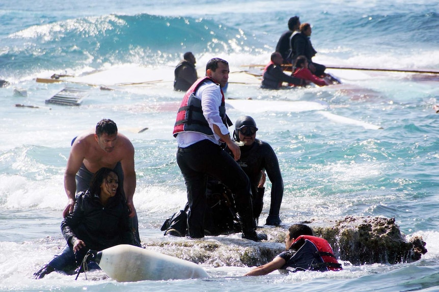 Rescue workers help migrants after their boat sinks off the Greek island of Rhodes