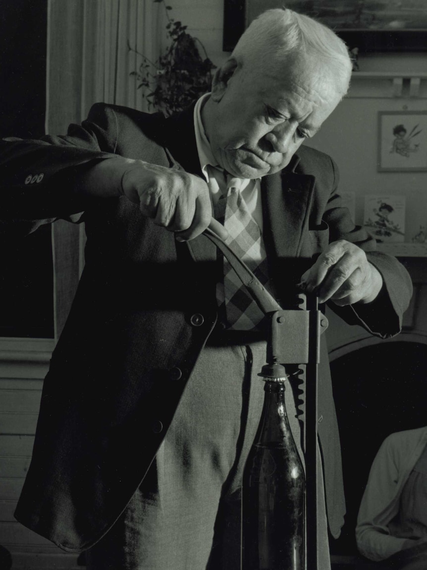 Black-and-white photo of William Panlook putting a cap on a homemade beer bottle.