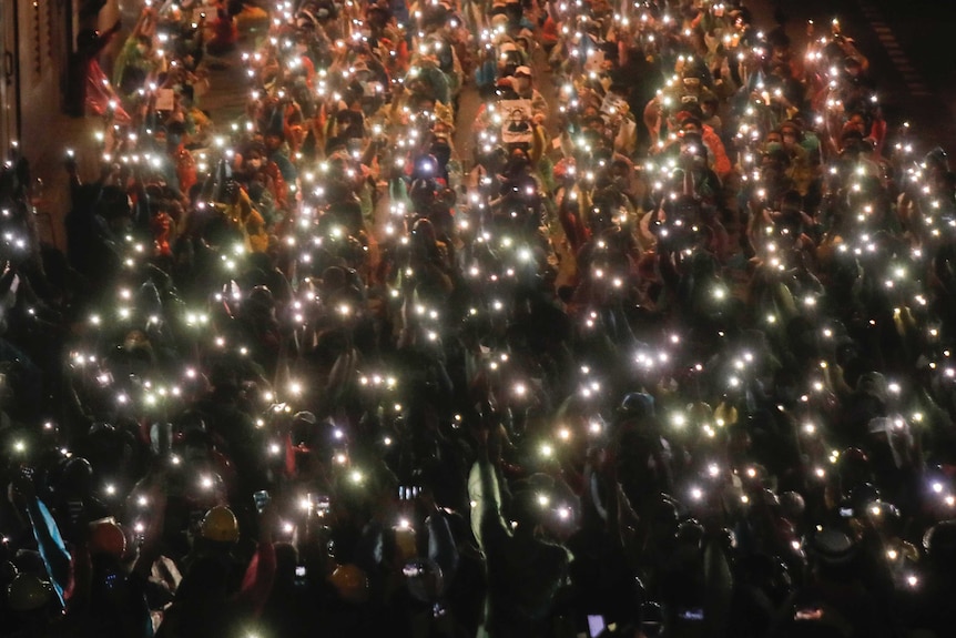 Pro-democracy protesters shine their mobile phone lights during an anti-government protest at Victory Monument in Bangkok.
