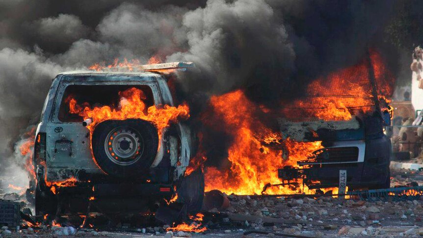 A Tunisian police car burns during a protest against the reopening of a rubbish dump.