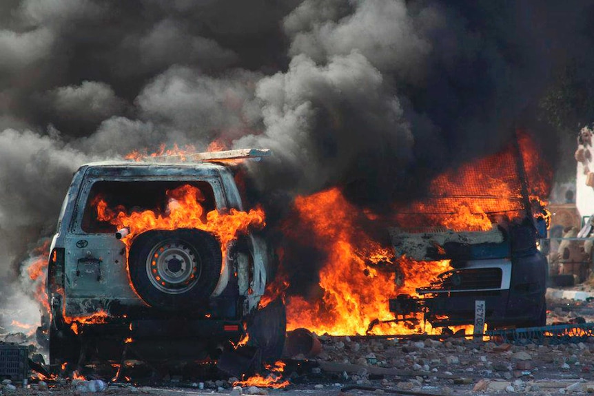 A Tunisian police car burns during a protest against the reopening of a rubbish dump.