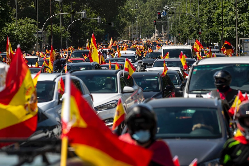 People wave Spanish flags during a drive-in protest organised by Spain's far-right Vox party.