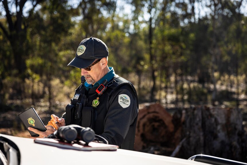 An authorised officer writes in his notebook while in a forest.