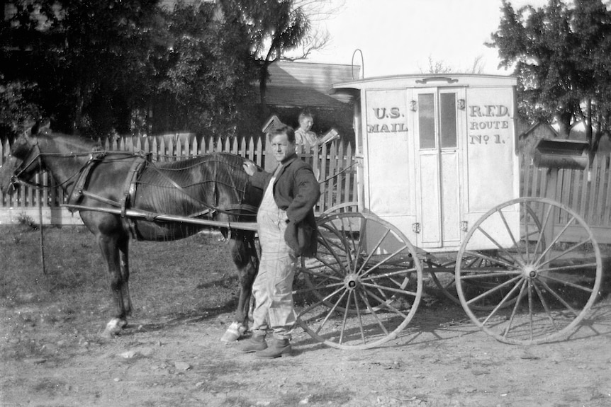 A photo of a mailman and his horse-drawn wagon.