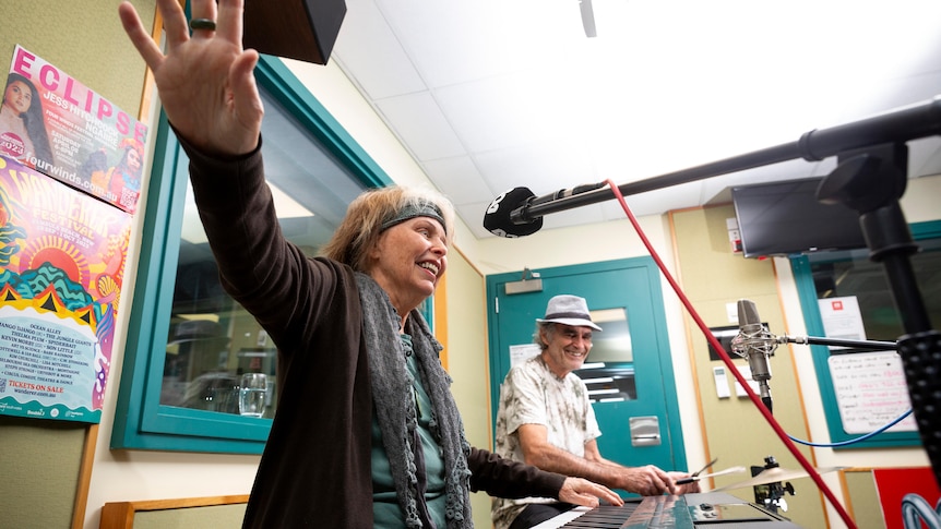 a woman performs lively into a microphone in an ABC radio studio