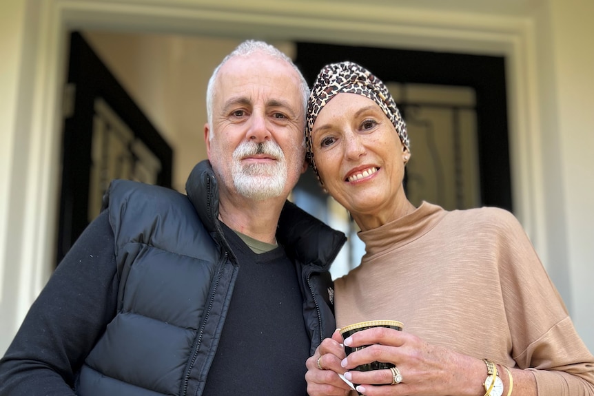 Suzi is wearing a leapord print head covering and standing with her partner Alex.