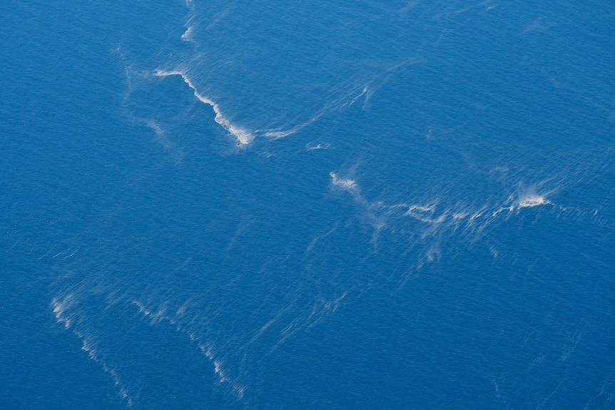 Oil slicks are seen in the ocean from an aerial view.