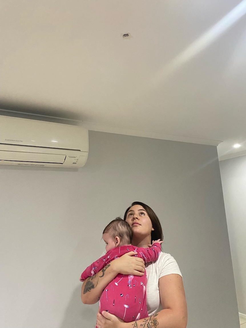 A woman holding a baby looking the the ceiling