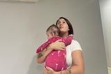 A woman holding a baby looking the the ceiling
