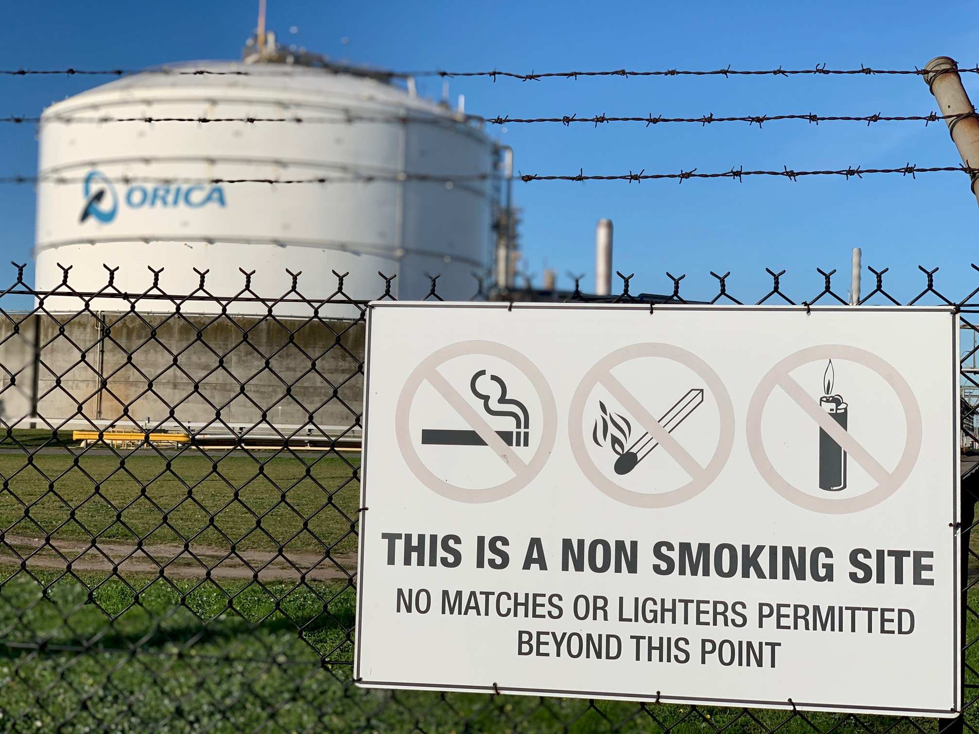 Photo of an industrial storage tank with a no smoking sign in front. 