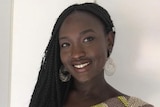 A woman with black skin and plaited hair and a brightly coloured shirt smiles at the camera