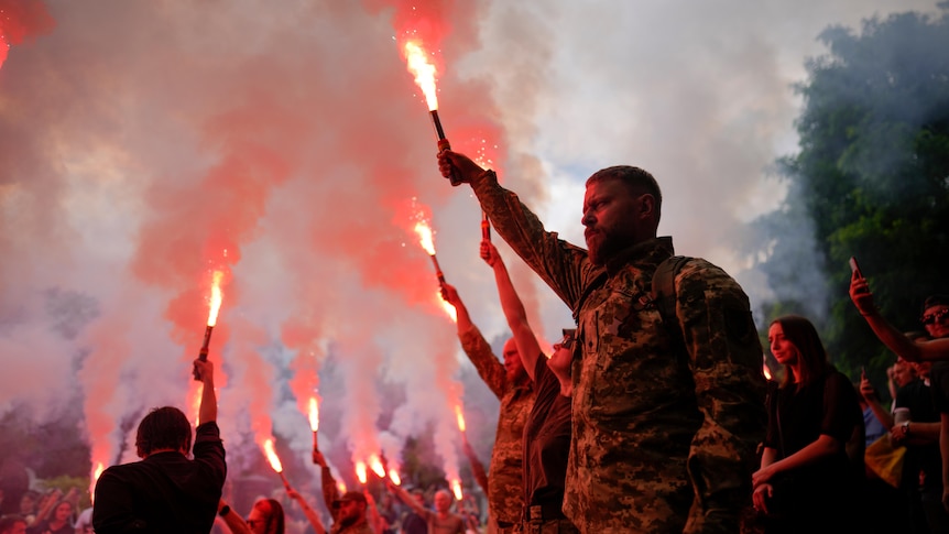 Soldiers hold flares as they attend the funeral of activist and soldier killed in Izyum.